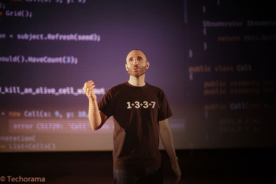 Enrico on stage at Techorama Belgium, in front of a wall of projected C# code